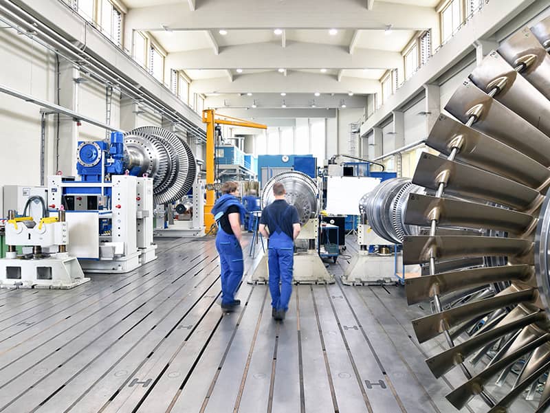 workers assembling and constructing gas turbines in a modern industrial factory