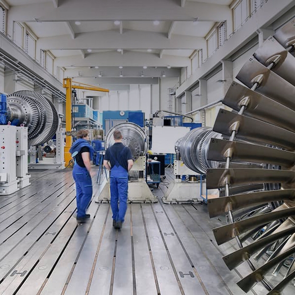 workers assembling and constructing gas turbines in a modern industrial factory