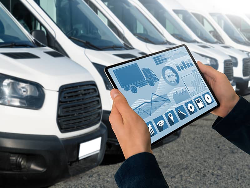 person holding a tablet in front of a row of fleet vans